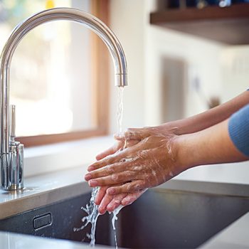 A person washing their hands with soap and water, promoting hygiene and cleanliness.